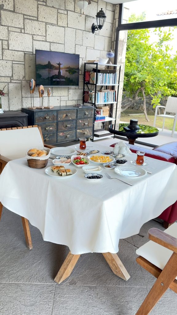 Turkish breakfast on a table in the hotel café, with a stone wall and a bookshelf behind