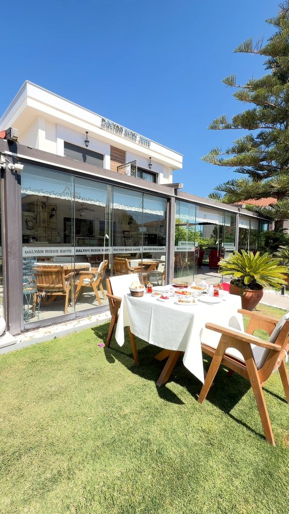 Dalyan Risus Suite: the hotel building with its glass-walled café and the lawn in front of it